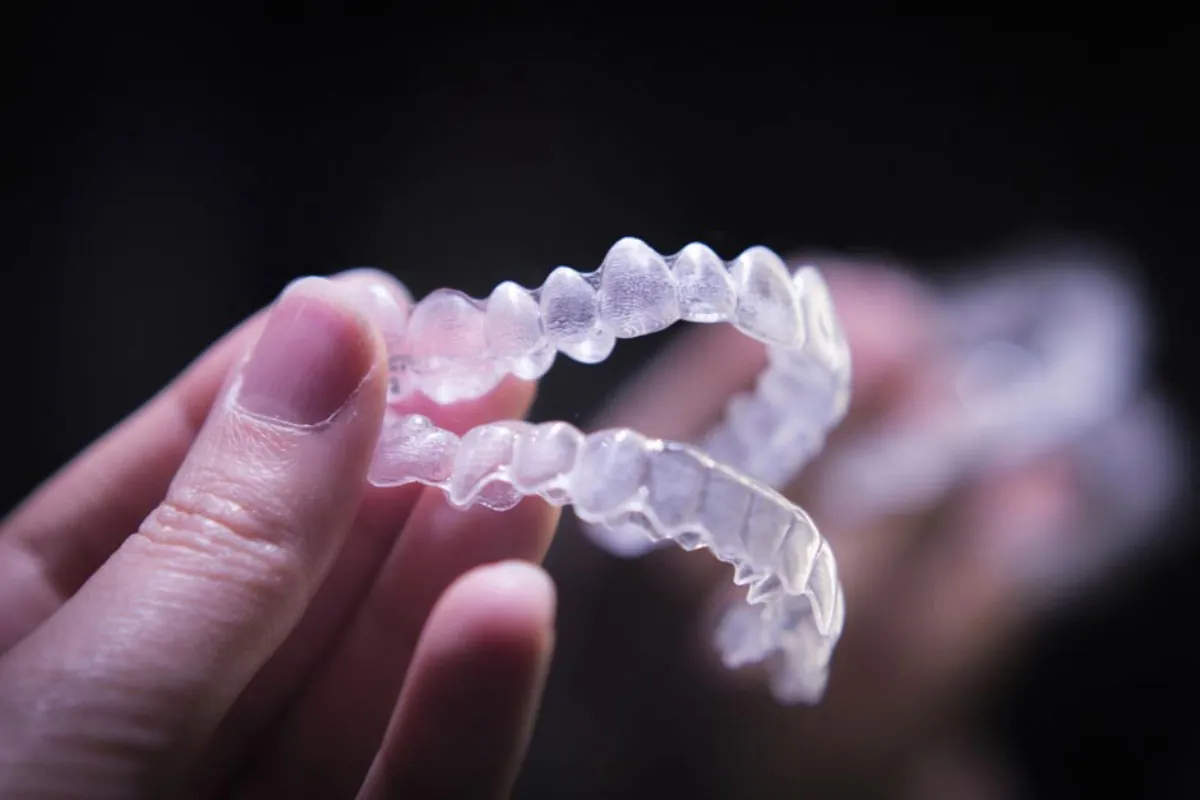 woman holding her new clear aligners from Rosehill Dentistry